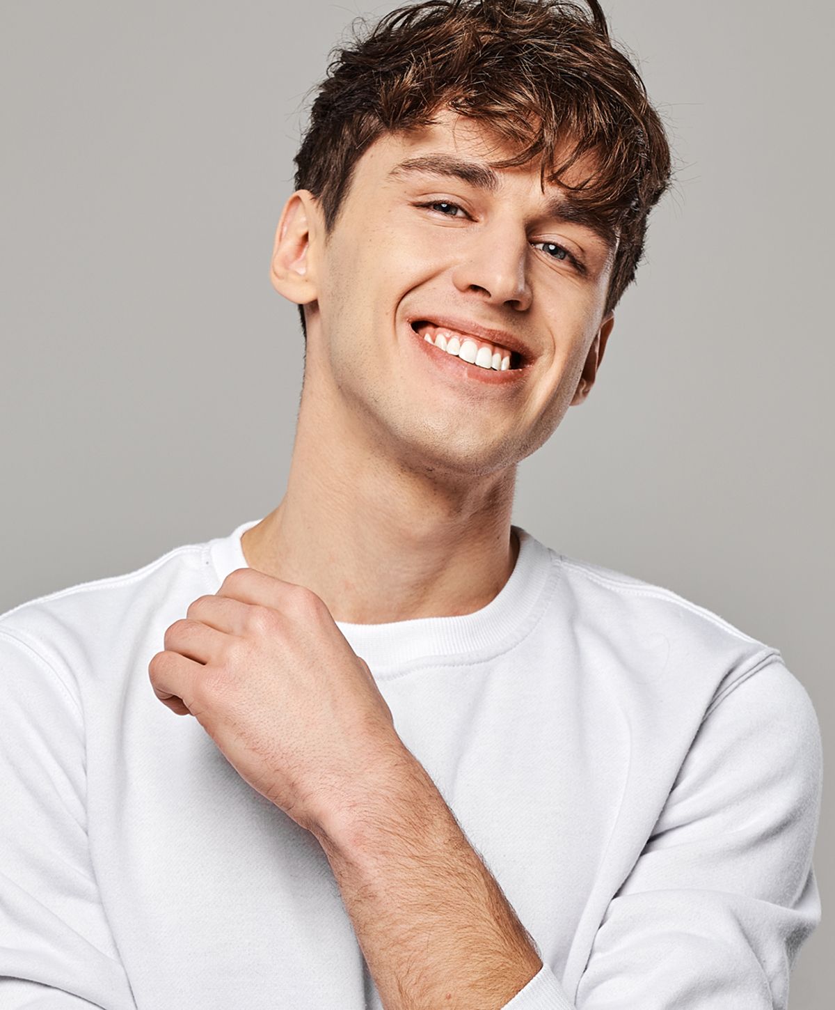 Smiling young man in a white sweatshirt.