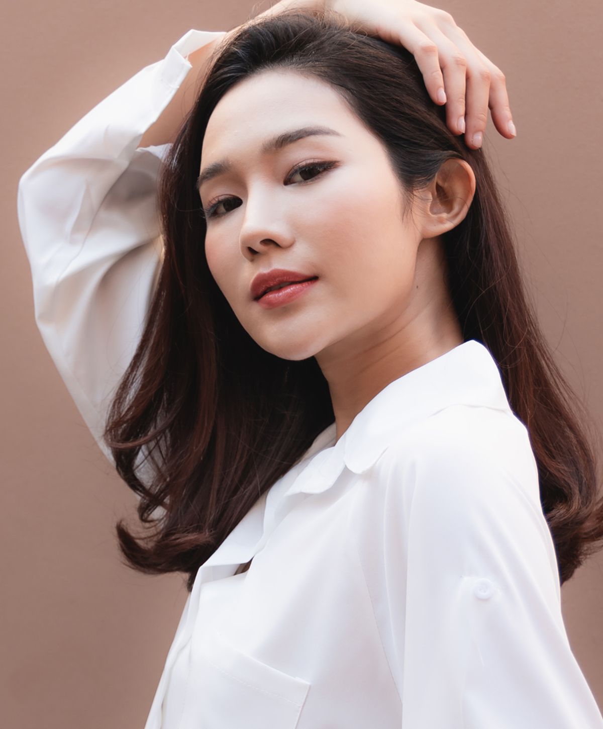 Young woman in white blouse posing confidently.