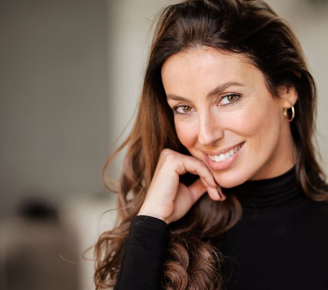 Smiling woman with long hair in black top.
