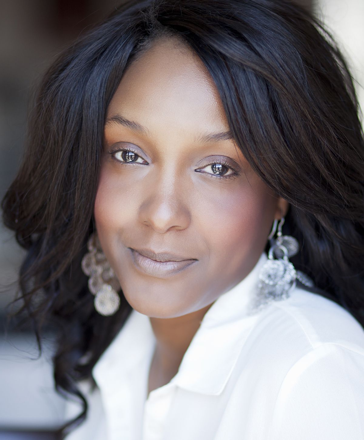 Woman with long hair and earrings, natural light.