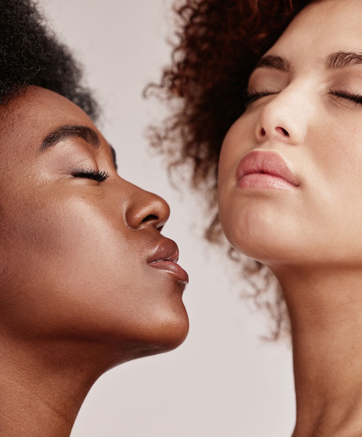 Two women with closed eyes and diverse hairstyles.