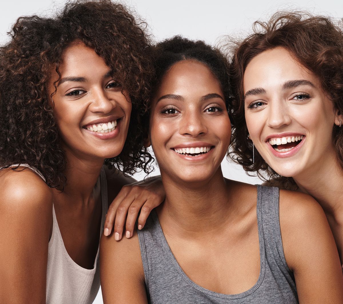 Three smiling women with curly hair.
