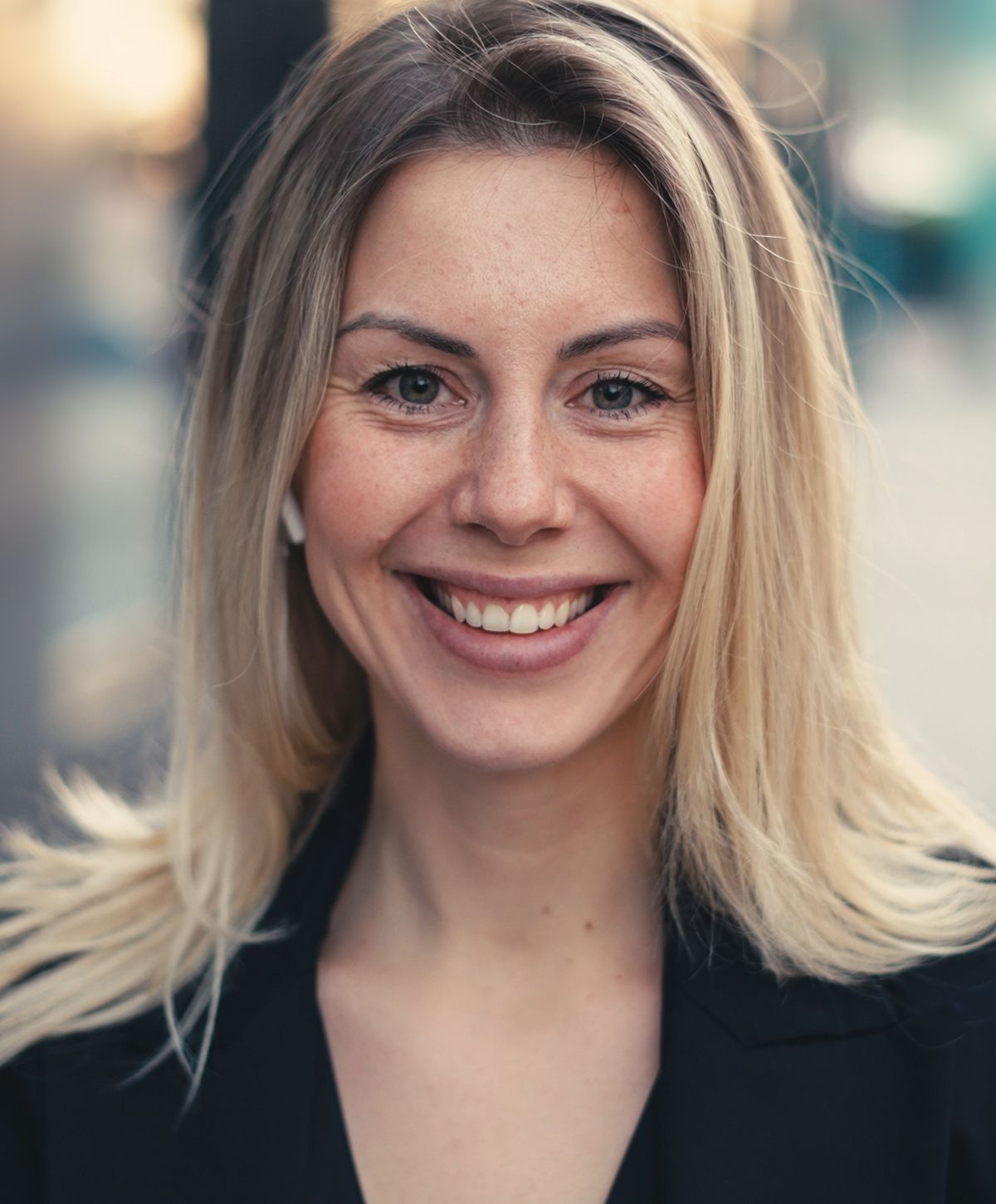 Smiling woman with blonde hair outdoors.