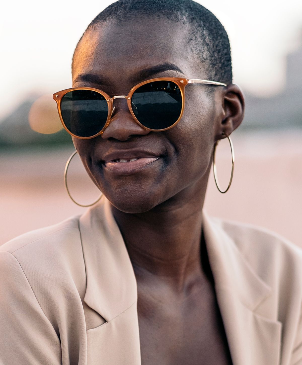 Person wearing stylish sunglasses and hoop earrings.