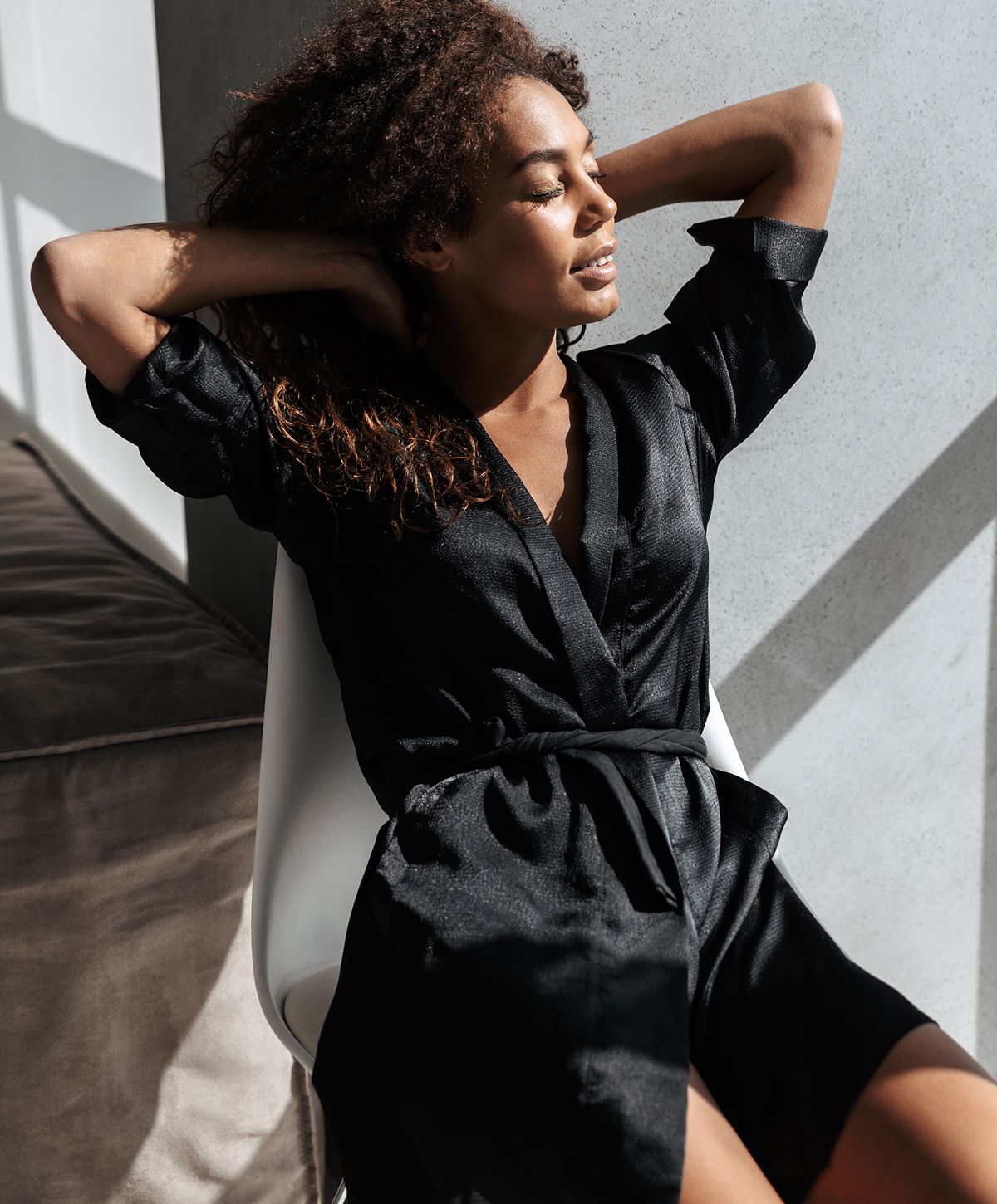 Woman relaxing in natural light, wearing black outfit.