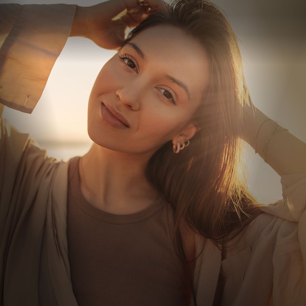 Smiling woman with long hair, soft sunlight glow.