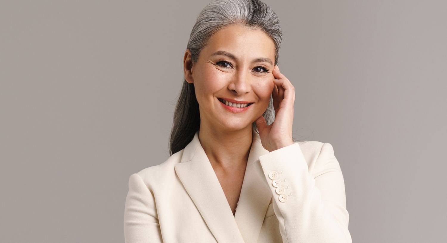 Smiling woman in cream blazer, gray hair.
