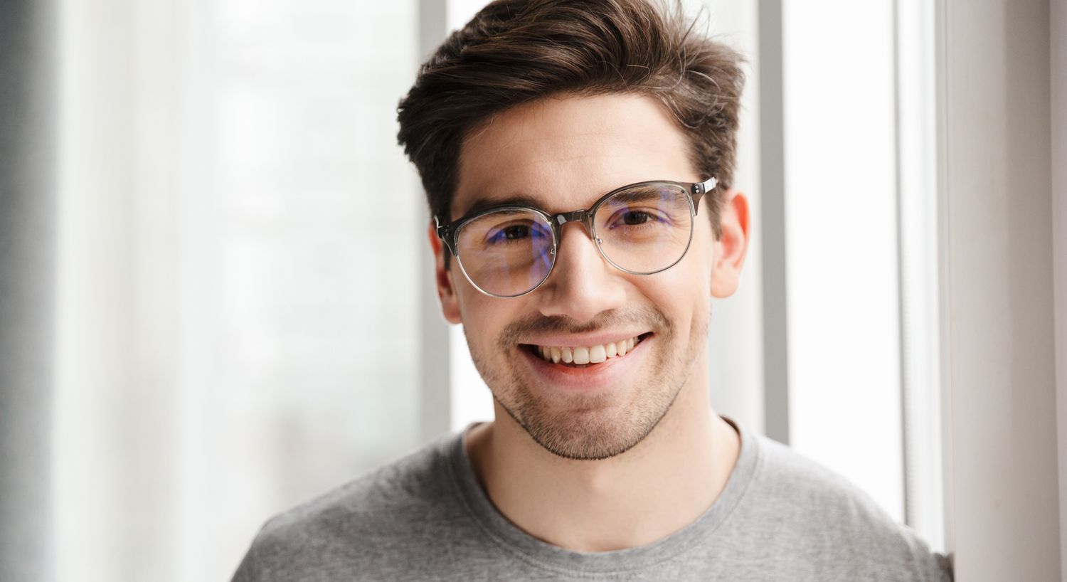 Smiling young man wearing glasses indoors.