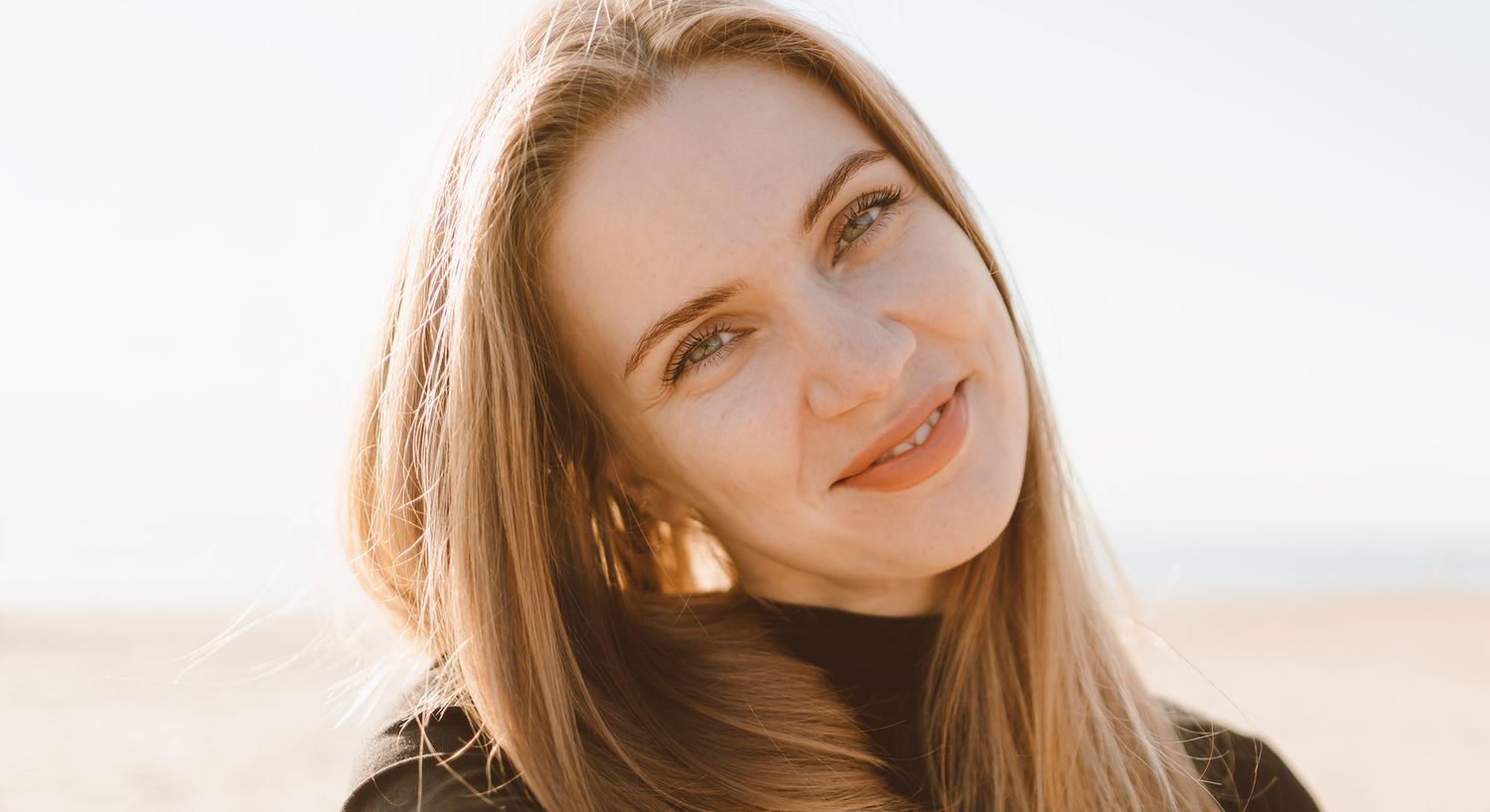 Smiling woman with long hair outdoors.