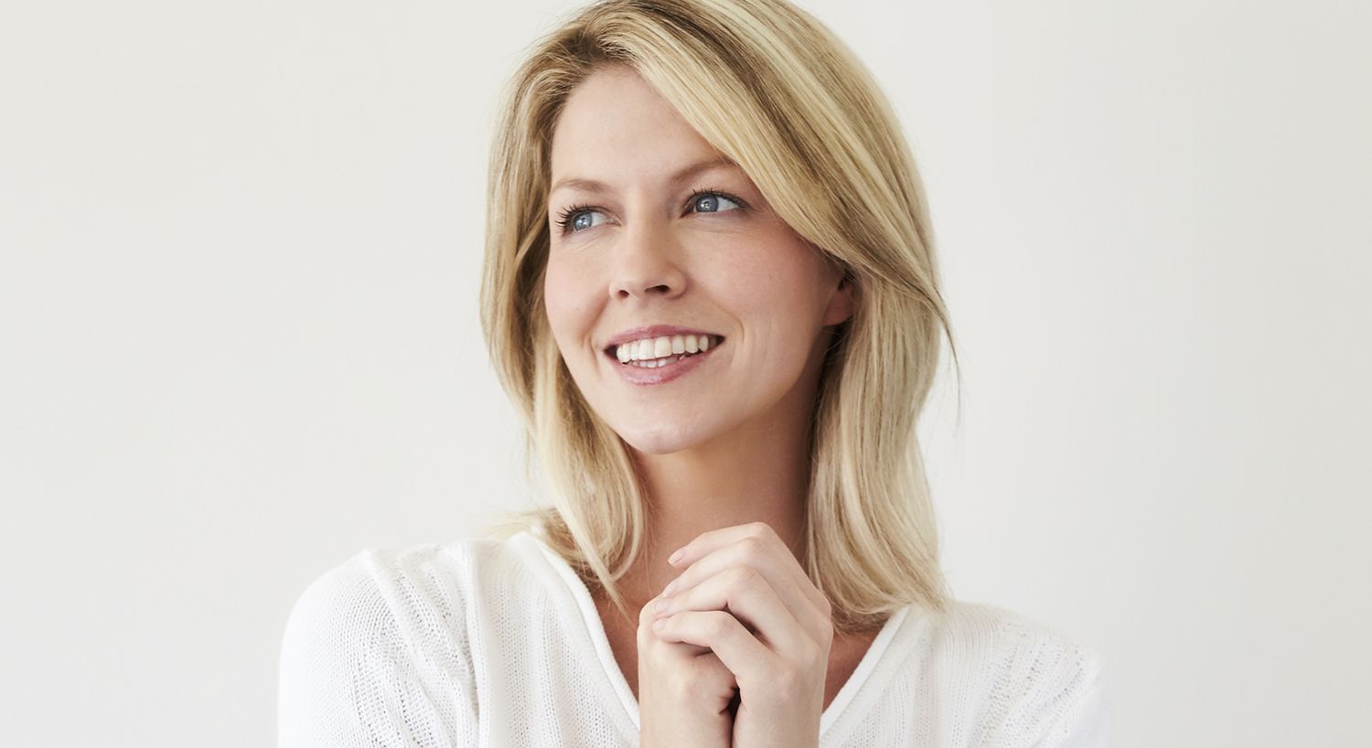 Smiling woman with blonde hair and white sweater.