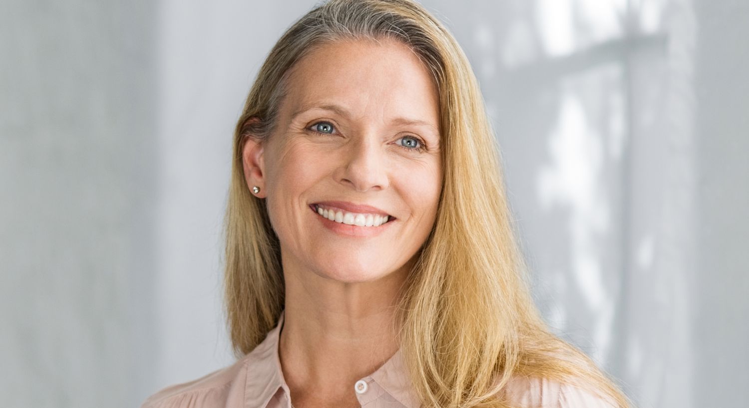 Smiling woman with long hair in soft lighting.