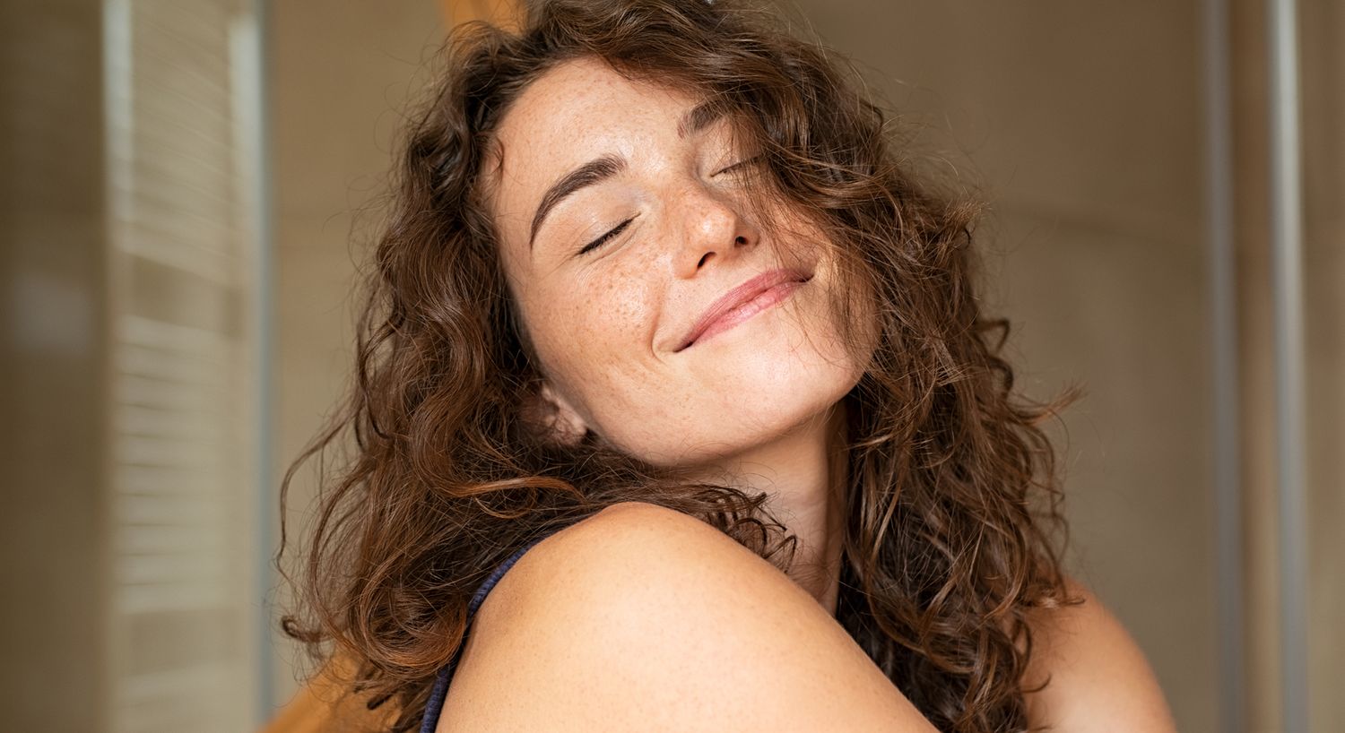 Smiling woman with curly hair and freckles.