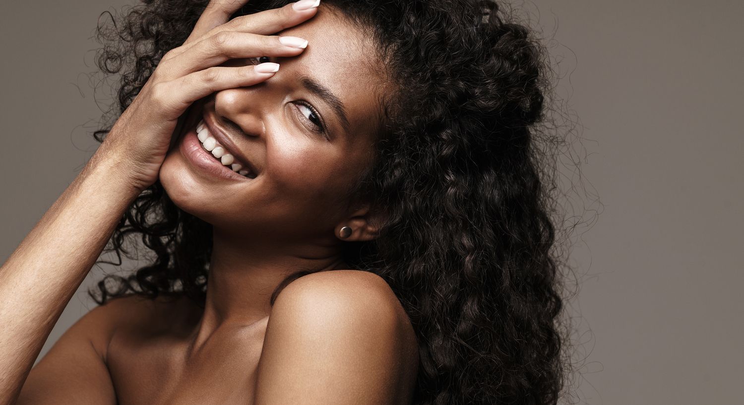 Smiling woman playfully covering her face.