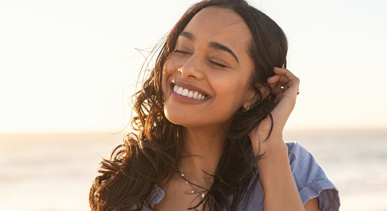 Smiling woman enjoying a sunny beach moment.