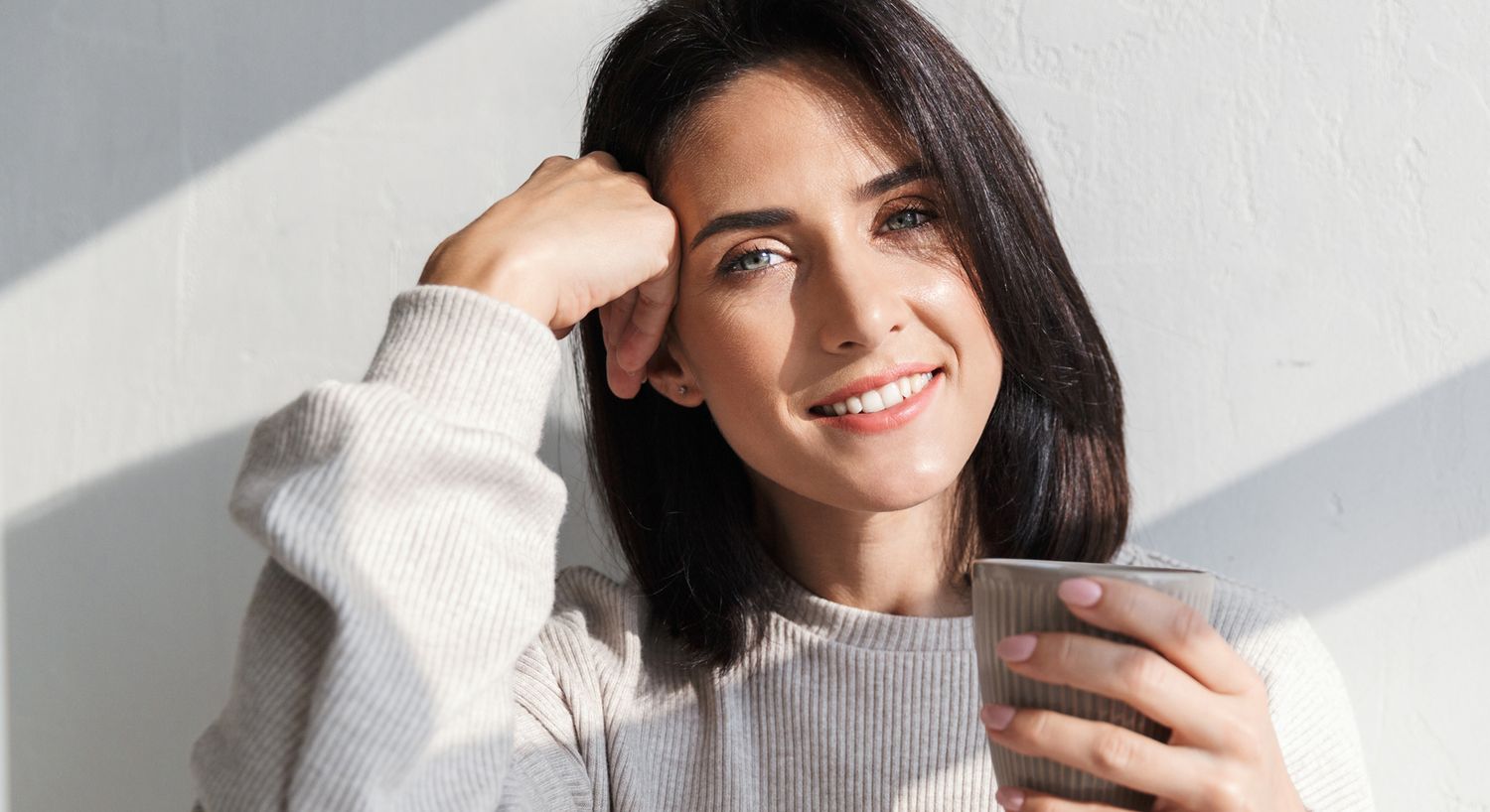 Woman enjoying a warm drink in sunlight.